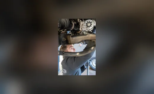 Mechaniker bei der Arbeit unter einem angehobenen Fahrzeug