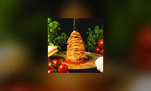 Spaghettiturm mit Basilikum und Tomaten vor dunklem Grund