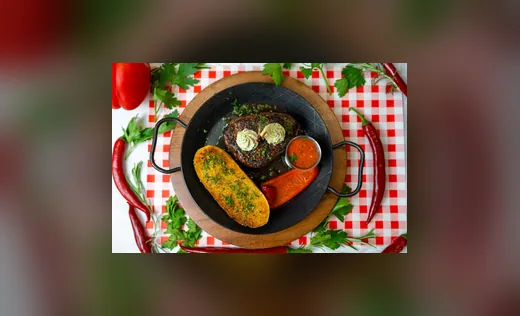 Angerichtete Pfanne mit Fleisch und Gemüse auf rot-weiß kariertem Tuch